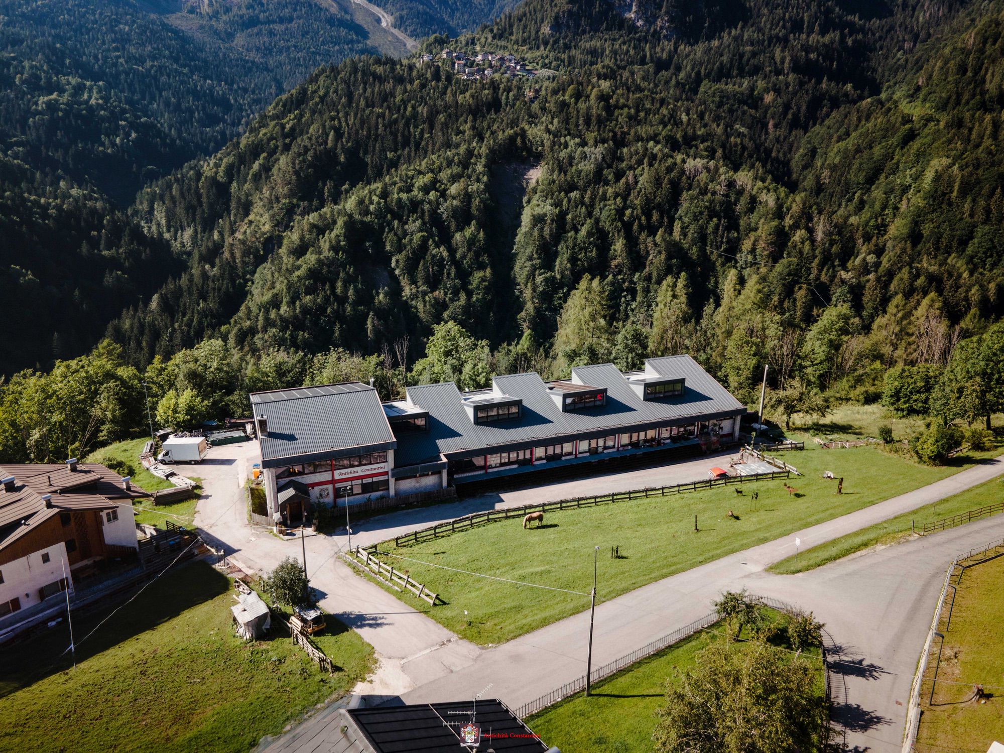 Veduta aerea della sede di Antichità Constantini a Venas di Cadore, circondata da prati e boschi di montagna