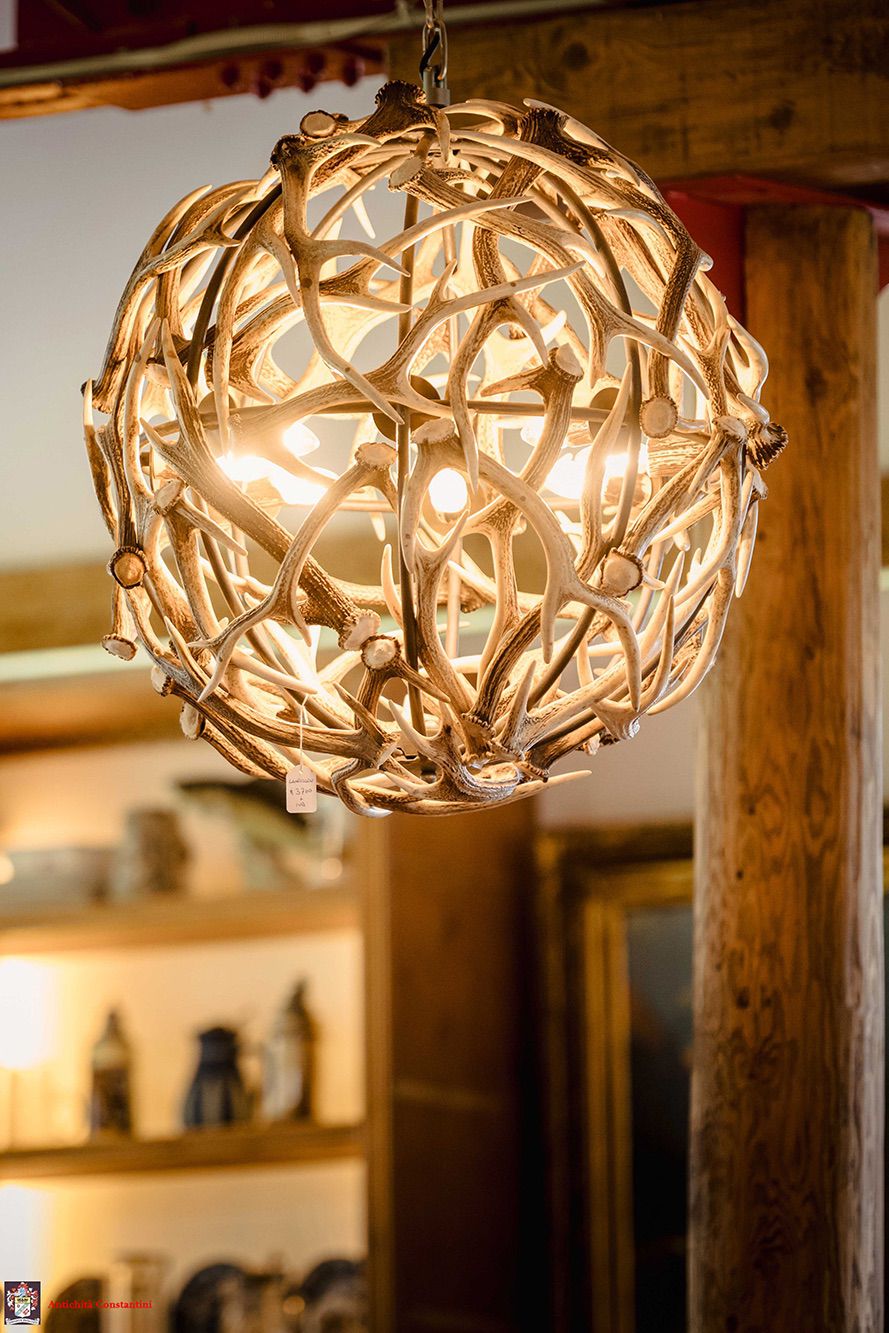 Lampadario a sfera formato da palchi intrecciati, acceso accanto a un tronco portante